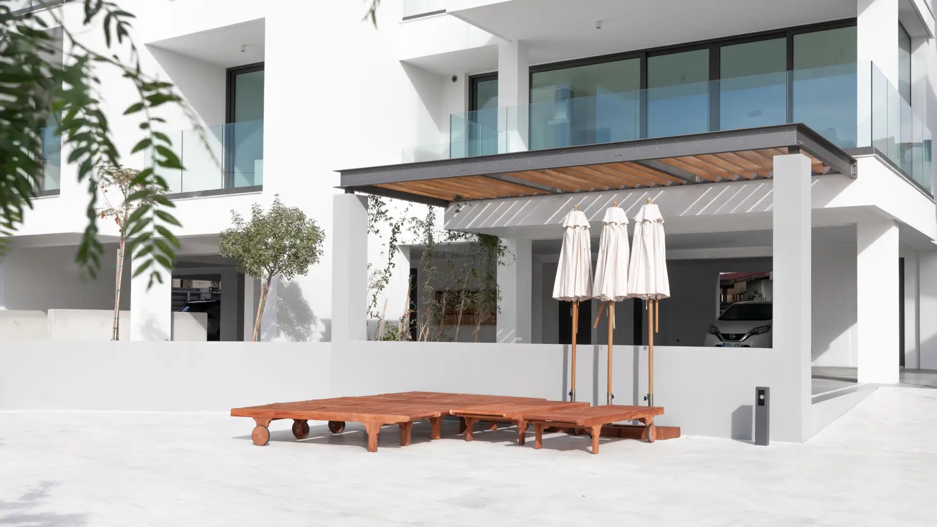 White apartment building with a shaded terrace, sun loungers and parasols