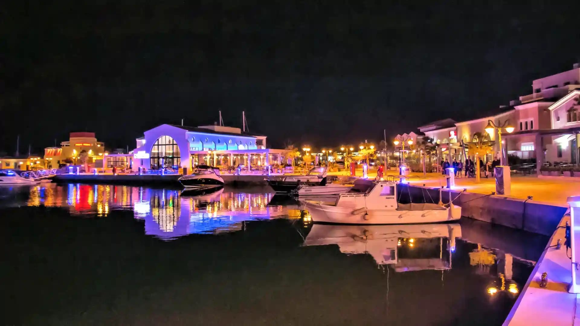 Limassol Marina lit up at night, with boats reflected in the water