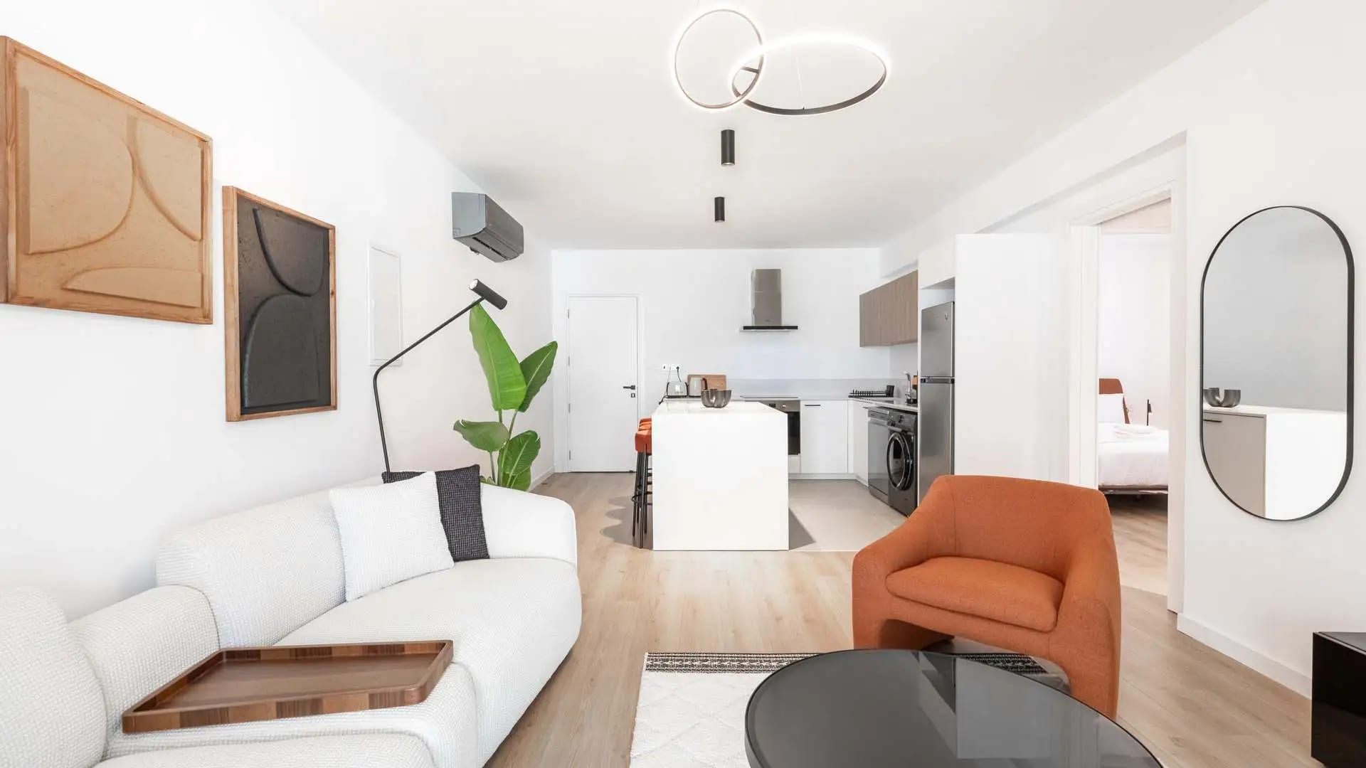 Bright open-plan apartment with a white sofa, an orange armchair and a kitchen island