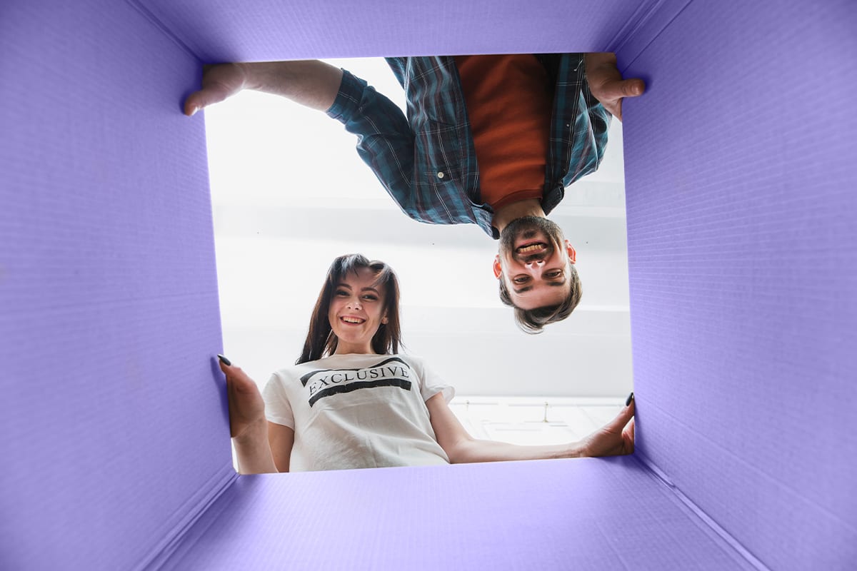 Smiling couple looking down into an open moving box